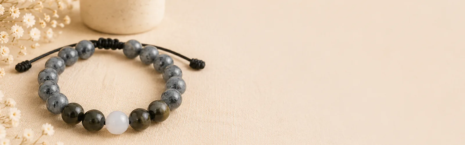 The Return Bracelet with its Moonstone Return Bead beside a softly lit remembrance candle